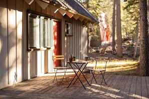 Une cabane en bois avec une véranda, une table et deux chaises.
