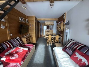 Ein gemütliches Blockhäuschen-Interieur mit einer Holzeinrichtungs-Essgruppe, einer Couch und einem Fernseher.