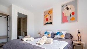 A modern bedroom with a large bed, bedside tables, a wardrobe, and abstract wall art.