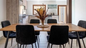 A dining area with a wooden table, black chairs, and pendant lighting.