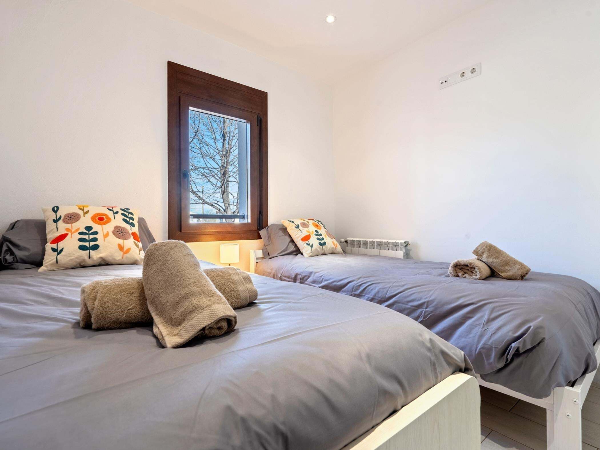 A bedroom with two beds, each with a pillow and a rolled towel.
