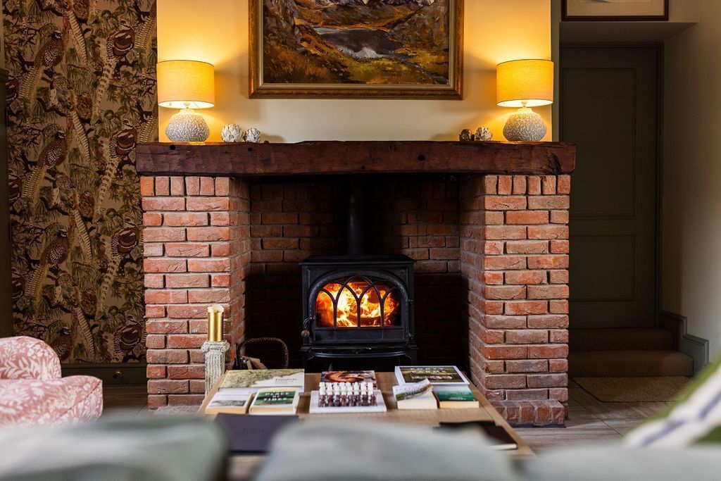 Una habitación acogedora con chimenea, una mesa con libros y un cuadro sobre la chimenea.
