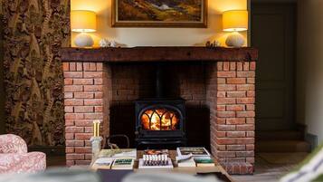 Una habitación acogedora con chimenea, una mesa con libros y un cuadro sobre la chimenea.
