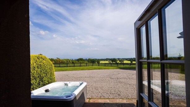 A hot tub outside a building with a view of a gravel area and a fence. - Drake's Rest, Kirklinton -  a cottage that sleeps 2 guests  in 1 bedroom (Kirklinton)