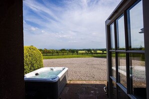 Un jacuzzi al aire libre frente a un edificio, con vistas a un área de grava y una cerca.