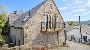A stone building with a balcony, a chimney, and a small window. - Romantic cottage with lake view in Bowness on Windermere (Bowness on Windermere)