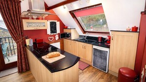 A kitchen with a central island, wooden cabinets, a red refrigerator, and a window with a view. - Romantic cottage with lake view in Bowness on Windermere (Bowness on Windermere)