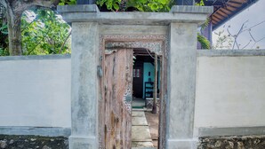 A doorway with intricate carvings, leading to a building with a tiled roof and a visible staircase. - Moonlight Villa Ceningan (Ceningan Island)