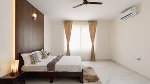 A bedroom with a bed, nightstand, wall-mounted air conditioning unit, ceiling fan, and a window with curtains. - Casa Miro by Red Olive 4bhk Hebbal Bangalore (Bengaluru)