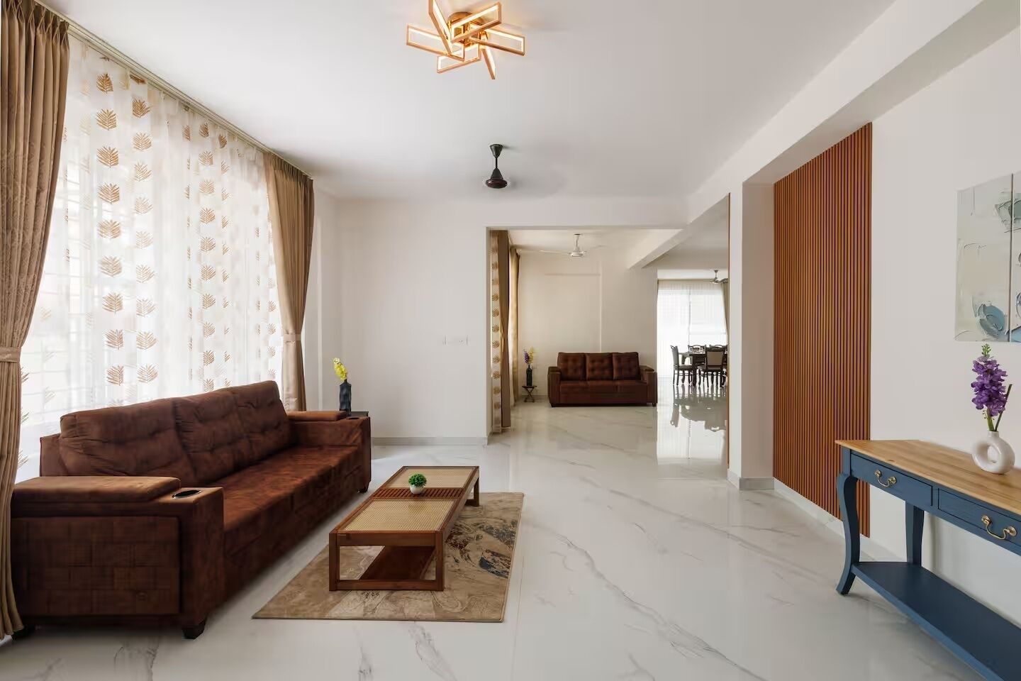 A modern living room with a brown sofa, a coffee table, and a blue console table with a vase.