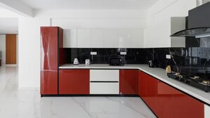 A modern kitchen with white and red cabinetry, a black countertop, and a stainless steel range hood. - Casa Miro by Red Olive 4bhk Hebbal Bangalore (Bengaluru)