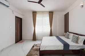 Ein Schlafzimmer mit Bett, Vorhängen, Deckenventilator und Fenster.