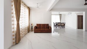 Amplia sala de estar con un sofá marrón, un comedor con mesa y sillas, y un ventilador de techo.