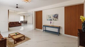 Una sala de estar moderna con sofá, mesa de centro y consola. En el fondo, hay un comedor.