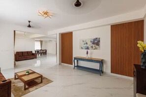 A modern living room with a sofa, coffee table, and console table. There is a dining area in the background. - Casa Miro by Red Olive 4bhk Hebbal Bangalore (Bengaluru)