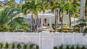 A gated residential area with a covered patio, palm trees, and a pathway leading to a building. - Pass A Grille (St. Pete Beach)
