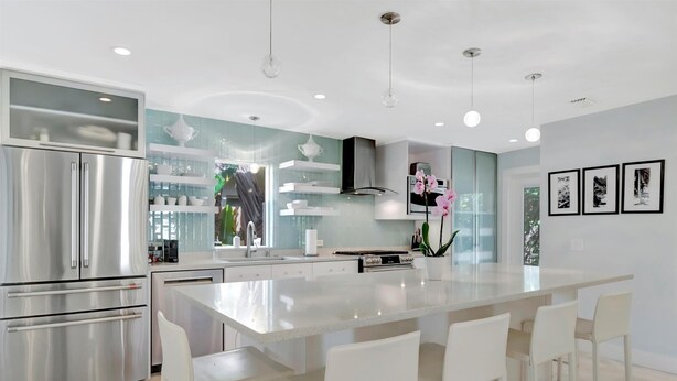 A modern kitchen with a large island, stainless steel appliances, and pendant lighting. - Pass A Grille (St. Pete Beach)