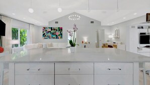A modern kitchen with a large island, white cabinetry, and pendant lighting. - Pass A Grille (St. Pete Beach)