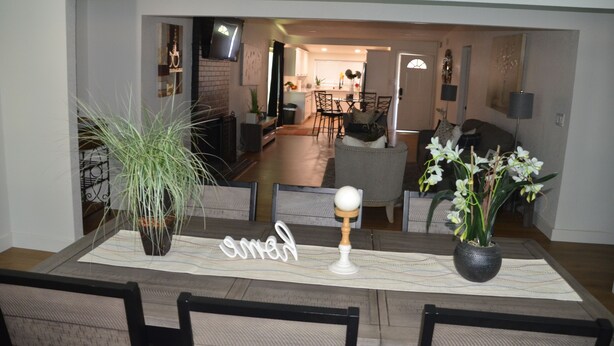A dining area with a table set for two, featuring a potted plant, a decorative item, and a sign. - House with A Vibe in West Sacramento A Swimming Pool and five bedrooms. (West Sacramento)