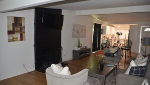 A living room with a fireplace, a dining area, and a kitchen in the background. - House with A Vibe in West Sacramento A Swimming Pool and five bedrooms. (West Sacramento)