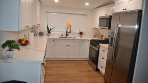 A modern kitchen with white cabinets, a stainless steel refrigerator, a microwave, and a wooden floor. - House with A Vibe in West Sacramento A Swimming Pool and five bedrooms. (West Sacramento)