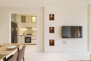 Eine moderne Küche mit Essbereich, einem an der Wand montierten Flachbildfernseher und einem Marmorboden.