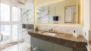 A modern bathroom with a large mirror, a marble sink, and a glass shower enclosure. - Casa Opal by Red Olive1bhkleela Residency (Bengaluru)