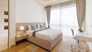 A modern hotel room with a large bed, bedside table with a lamp, a desk, and a chair. - Casa Opal by Red Olive1bhkleela Residency (Bengaluru)