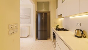 A modern kitchen with a stainless steel refrigerator, white cabinets, and a countertop with a kettle. - Casa Opal by Red Olive1bhkleela Residency (Bengaluru)