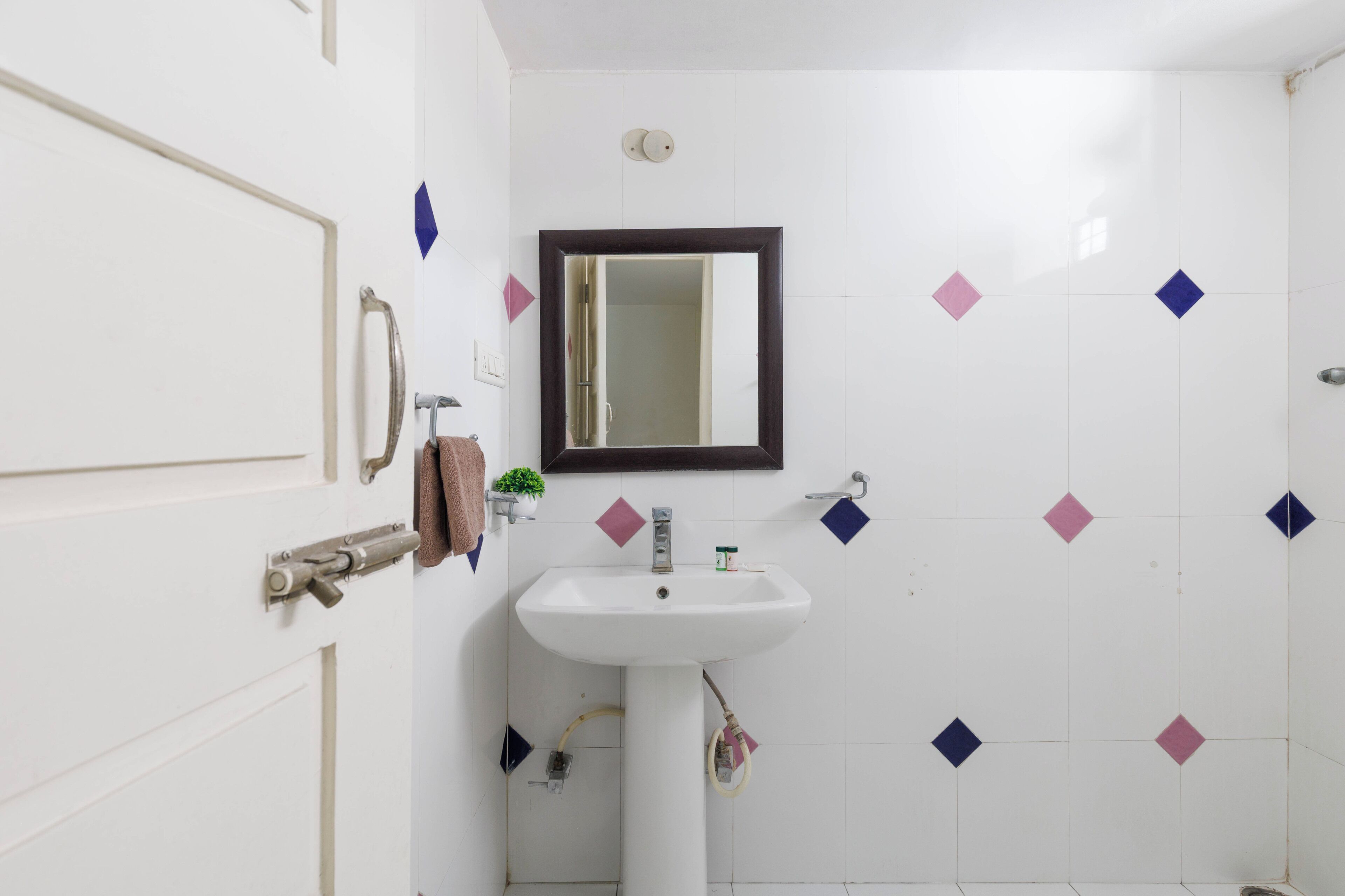 A bathroom with a white sink, a mirror, and a door with a handle.