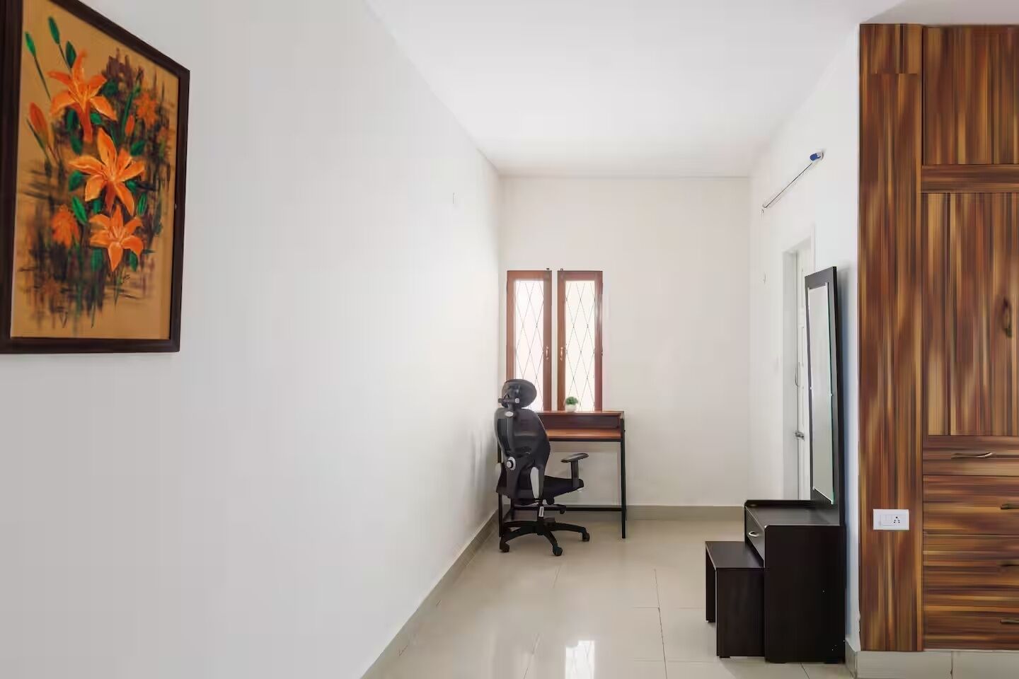 A room with a desk, chair, and a television.