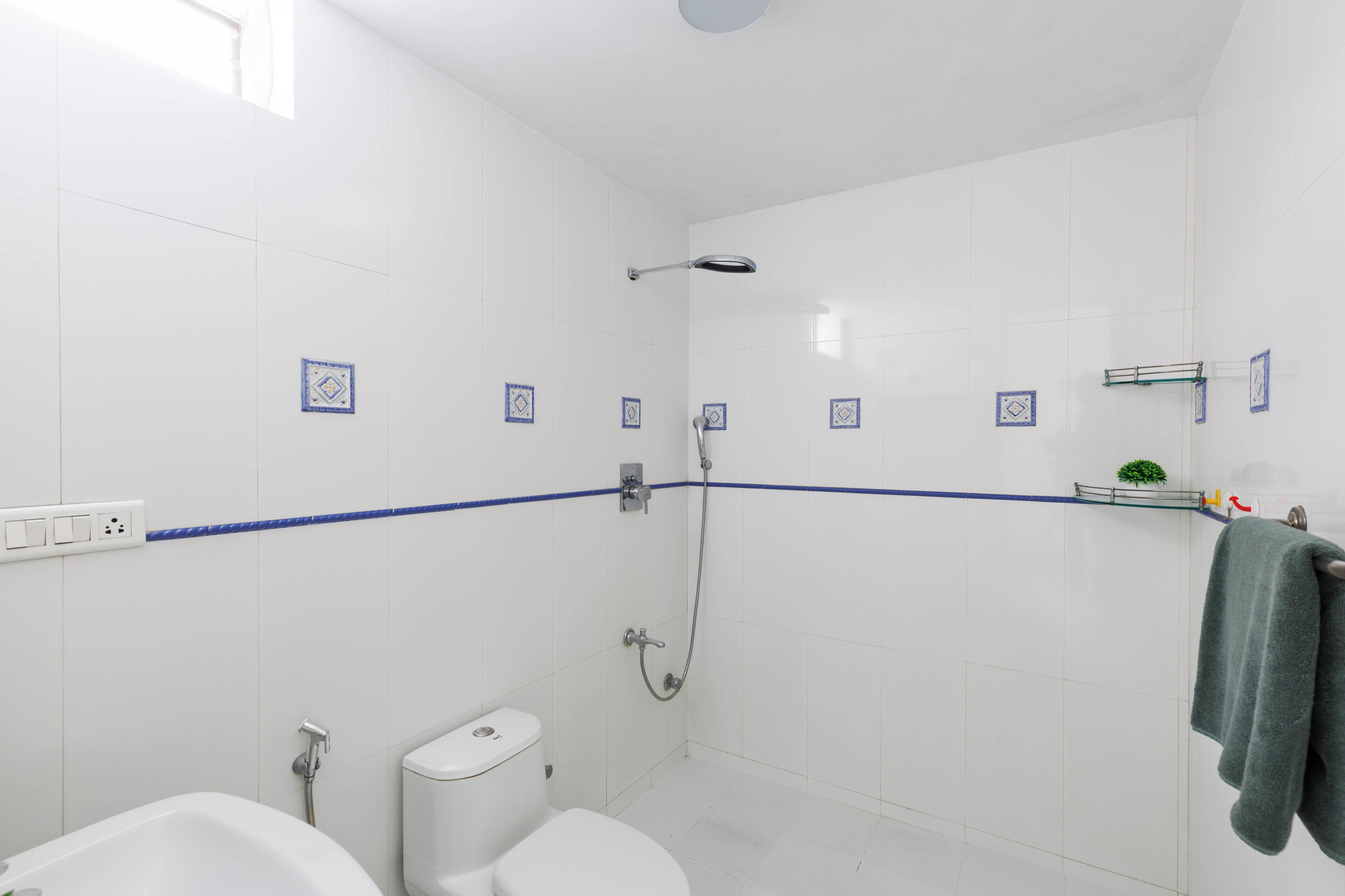 Ein Badezimmer mit weißen Fliesen, einer Dusche, einer Toilette und einer Badewanne.