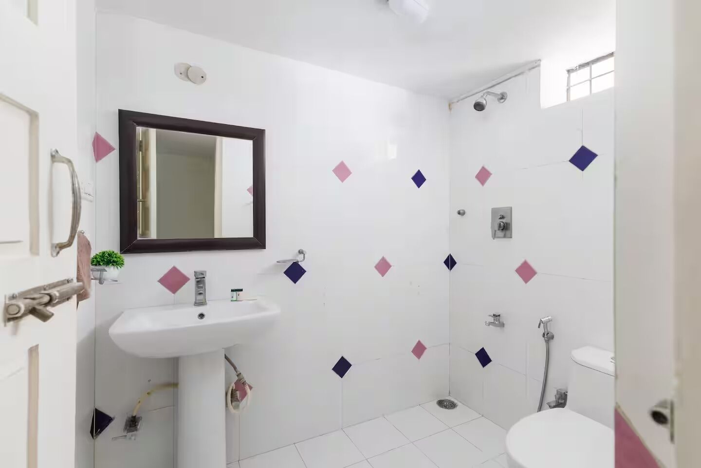 A bathroom with a white sink, a mirror, a shower, and a toilet.