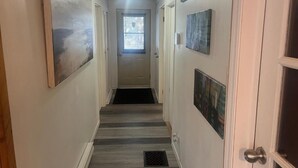 Un couloir avec une porte au fond, bordé de murs ornés d’œuvres d’art encadrées.