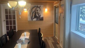 Un coin repas avec une table en bois, des chaises, un lustre et un tableau au mur.