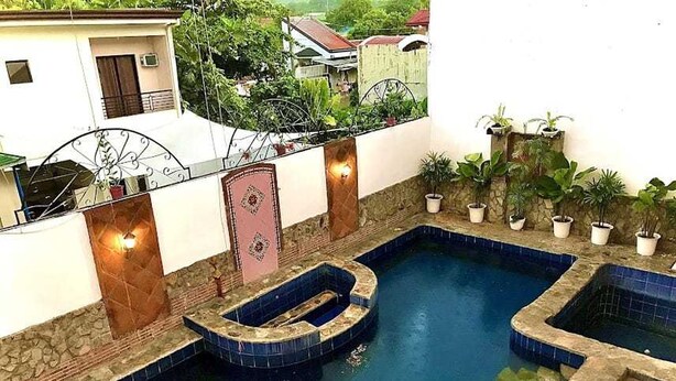 A swimming pool with two hot tubs, surrounded by potted plants and a stone wall. - OYO 1190 Manzel Shanicaye Private Villa (Calamba)