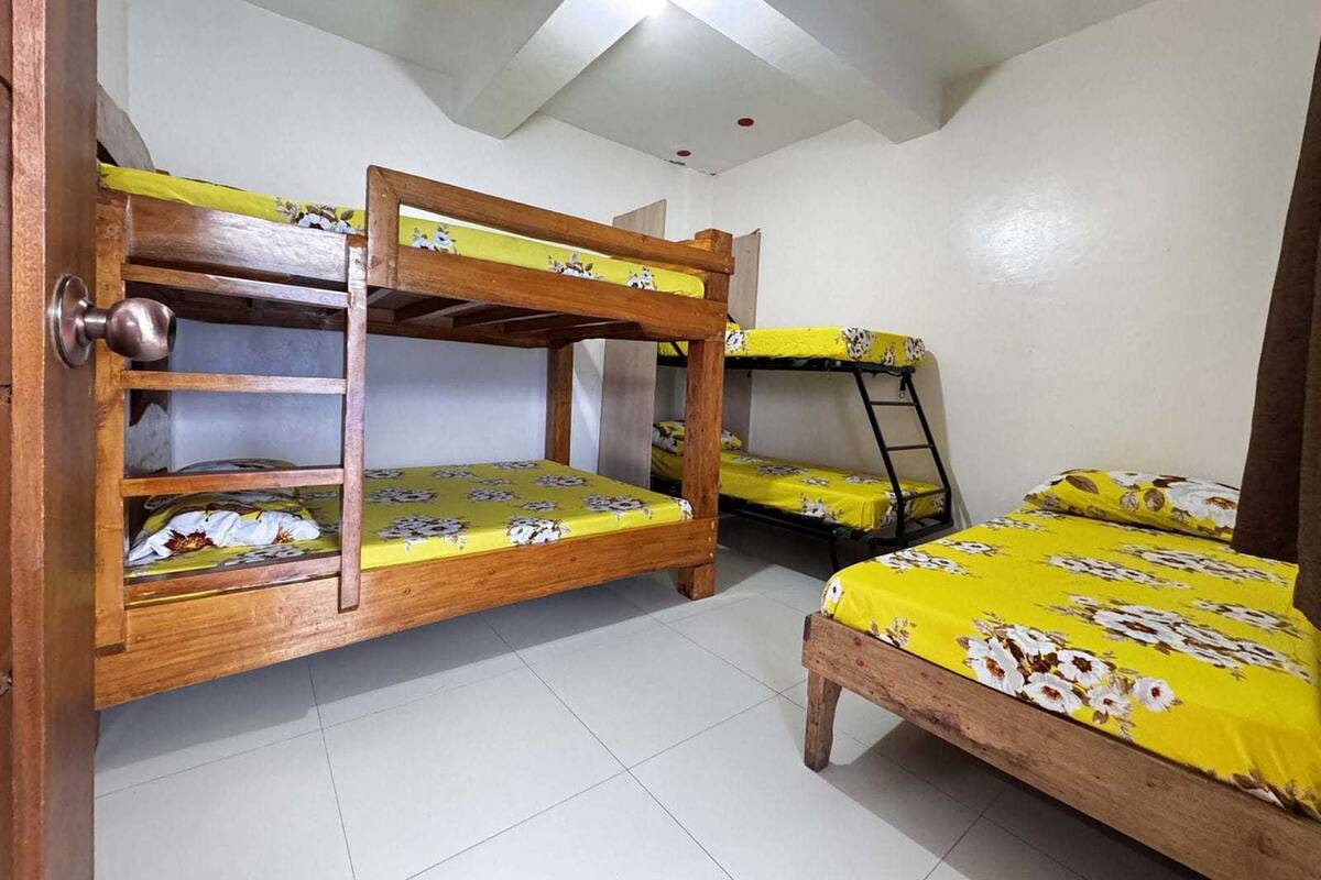 Un dormitorio con literas, una puerta de madera y suelo de baldosas.