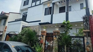 A two-story building with a white facade, black window frames, and a decorative gate with a sign. - OYO 1190 Manzel Shanicaye Private Villa (Calamba)