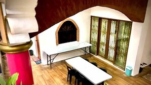 A kitchen with a built-in oven, a dining table with chairs, and a large window with curtains. - OYO 1190 Manzel Shanicaye Private Villa (Calamba)