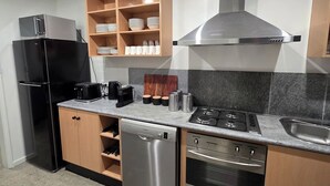 A modern kitchen with a black refrigerator, wooden cabinets, a stainless steel dishwasher, a gas stove, and a built-in oven. - A Sporting Spot in Warm Sunshine (Sunshine North)