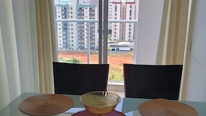 Une table à manger avec quatre chaises, un grand vase décoratif placé au centre et un set de table rouge.