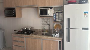 Une cuisine dotée de meubles en bois, d’une cuisinière à gaz, d’un four à micro-ondes, d’une machine à café et d’un réfrigérateur.