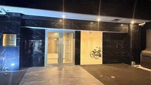 Entrada de un hotel con fachada de mármol, un letrero que dice 'Premier Phoenix' y una bicicleta estacionada en el interior.