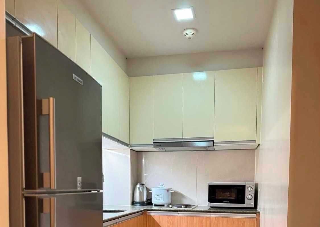 A compact kitchen with a refrigerator, microwave, and kettle.