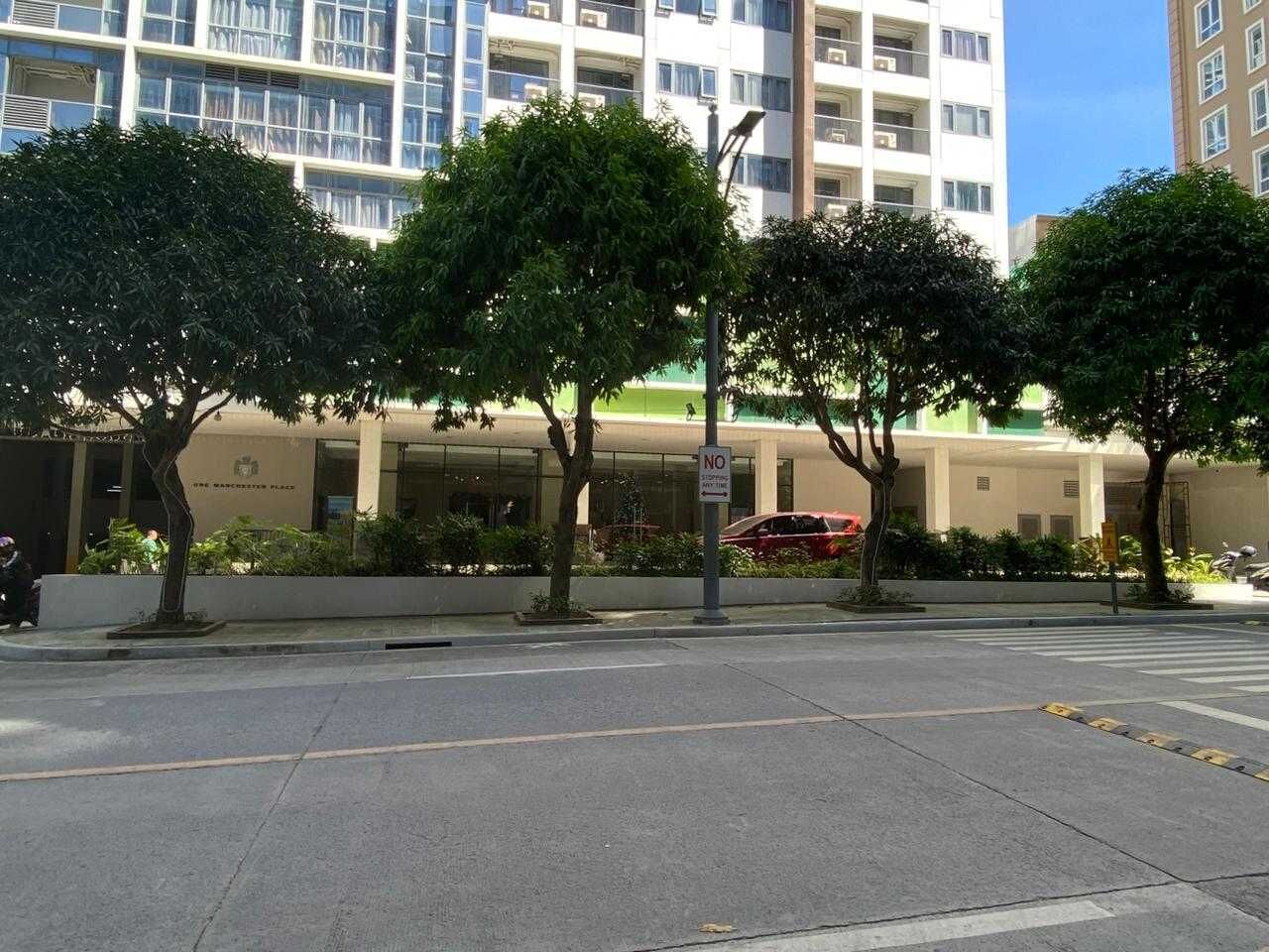 A street view with a building labeled "The Manchester Place" and a red car parked in front.