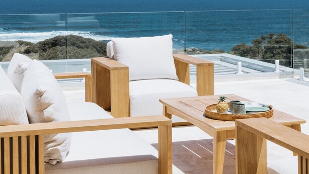 Una terraza con mobiliario de madera y vista al océano.