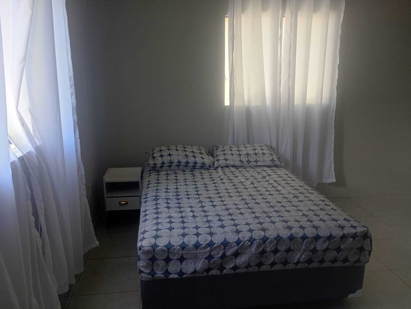 Une chambre à coucher avec un lit, une table de chevet et une fenêtre avec des rideaux.