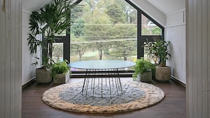A room with a round table, potted plants, and a view through a large window. - The Scent Boutique Dalat Hotel (Lam Vien - Da Lat)