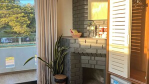 A room with a brick fireplace, a small refrigerator, a basket with snacks, and a potted plant. - The Scent Boutique Dalat Hotel (Lam Vien - Da Lat)
