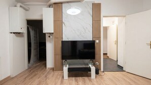 Una sala de estar moderna con un televisor de pantalla plana, panel de pared de madera y un respiradero en el techo.